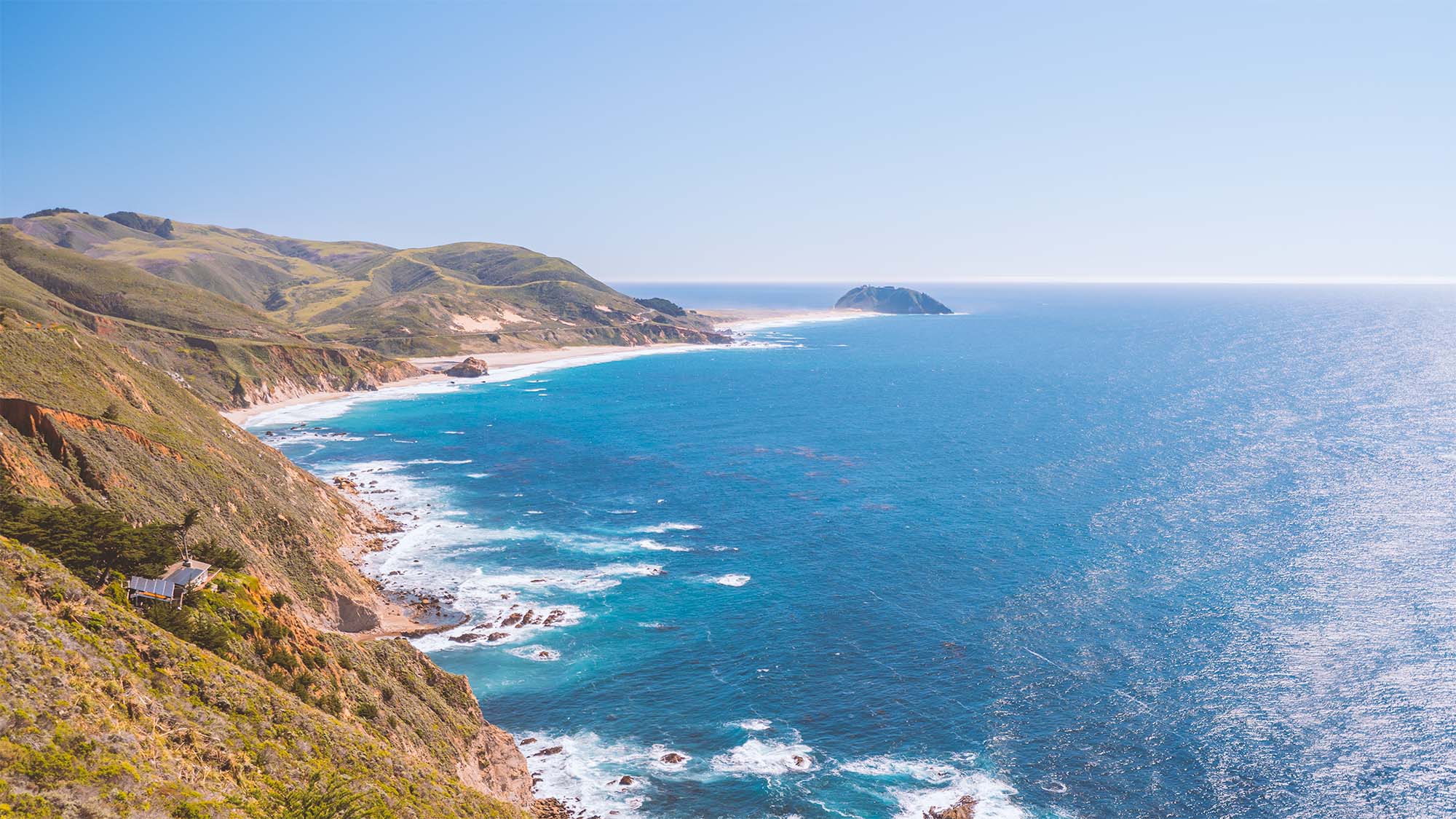 Scenic view of the Big Sur California coastal landscape with blue ocean and green hills.